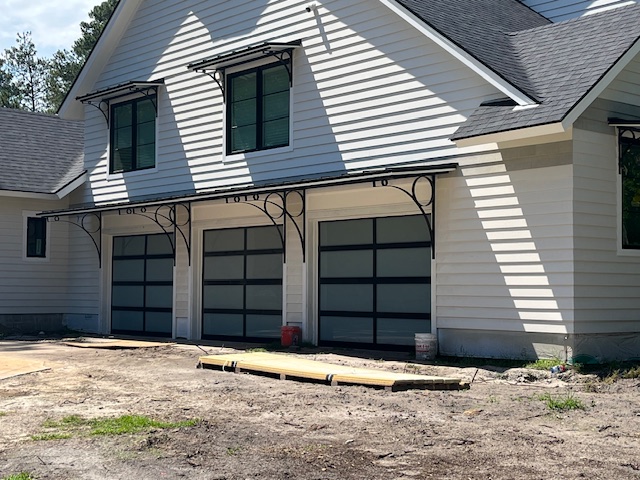 Three garage doors installed in a backyard setting